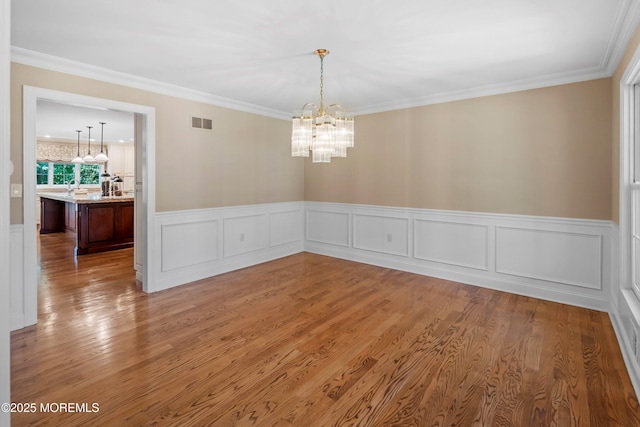 10 Woods Rd, West Long Branch, NJ 07764 - unfurnished room featuring a chandelier, wood finished floors, wainscoting, crown molding, and a sink