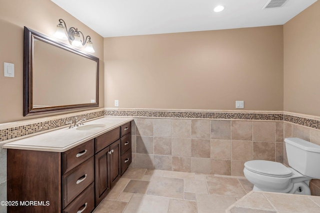 10 Woods Rd, West Long Branch, NJ 07764 - bathroom with tile walls, toilet, vanity, a wainscoted wall, and recessed lighting