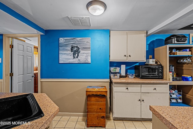 12 Central Ave, Waretown, NJ 08758 - kitchen with white cabinets, light countertops, light tile patterned flooring, a sink, and baseboards