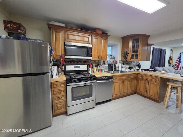 37 Beachway Ave, Keansburg, NJ 07734 - kitchen featuring stainless steel appliances, light countertops, brown cabinetry, glass insert cabinets, and decorative backsplash