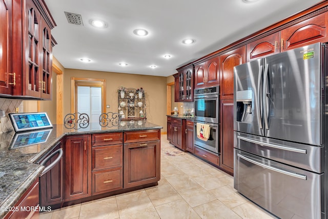 1 River Dr, Farmingdale, NJ 07727 - kitchen with appliances with stainless steel finishes, a peninsula, glass insert cabinets, backsplash, and dark stone counters