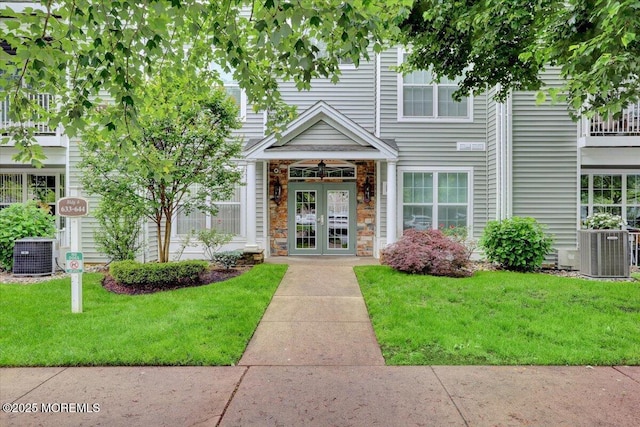 634 Saint Andrews Pl, Manalapan, NJ 07726 - view of front facade featuring french doors, a front lawn, central AC, and stone siding