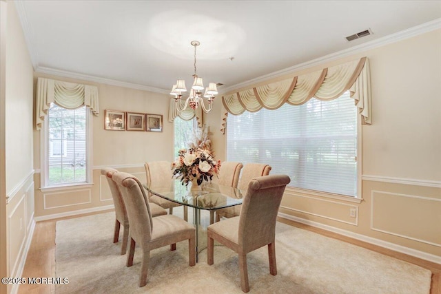 634 Saint Andrews Pl, Manalapan, NJ 07726 - dining space featuring a chandelier, crown molding, light wood finished floors, a decorative wall, and a wainscoted wall