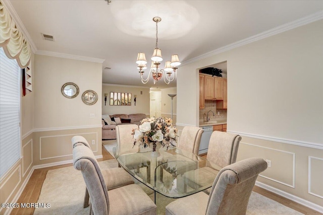 634 Saint Andrews Pl, Manalapan, NJ 07726 - dining space with a chandelier, ornamental molding, a decorative wall, and a wainscoted wall