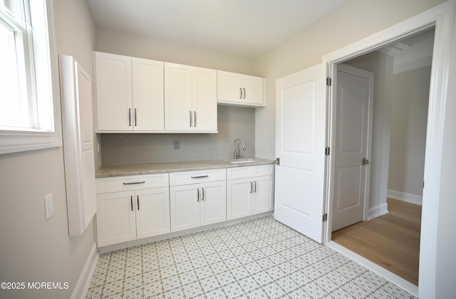 674 Lake Ave, Bay Head, NJ 08742 - kitchen featuring light countertops, white cabinets, tasteful backsplash, a sink, and baseboards
