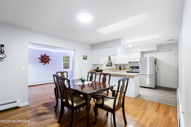 1015 Barnacle Dr, Manahawkin, NJ 08050 - dining room with baseboard heating, a skylight, a baseboard heating unit, and light wood-style flooring