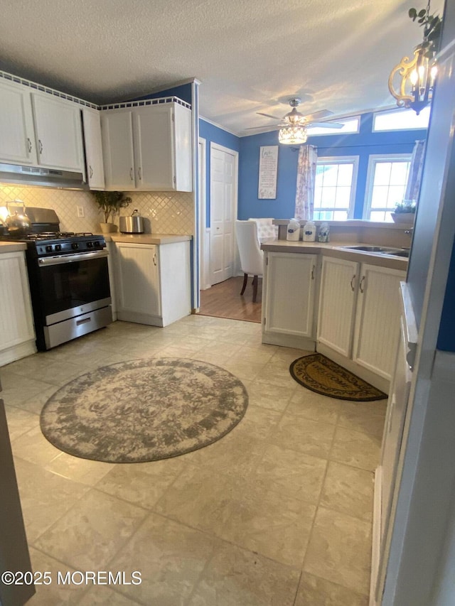89 Seattle Slew Dr, Howell, NJ 07731 - kitchen featuring stainless steel range with gas stovetop, under cabinet range hood, decorative backsplash, a sink, and a textured ceiling