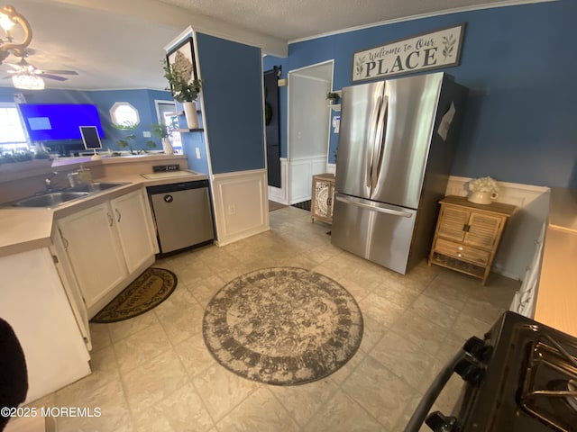 89 Seattle Slew Dr, Howell, NJ 07731 - kitchen featuring appliances with stainless steel finishes, a sink, a wainscoted wall, a textured ceiling, and ceiling fan