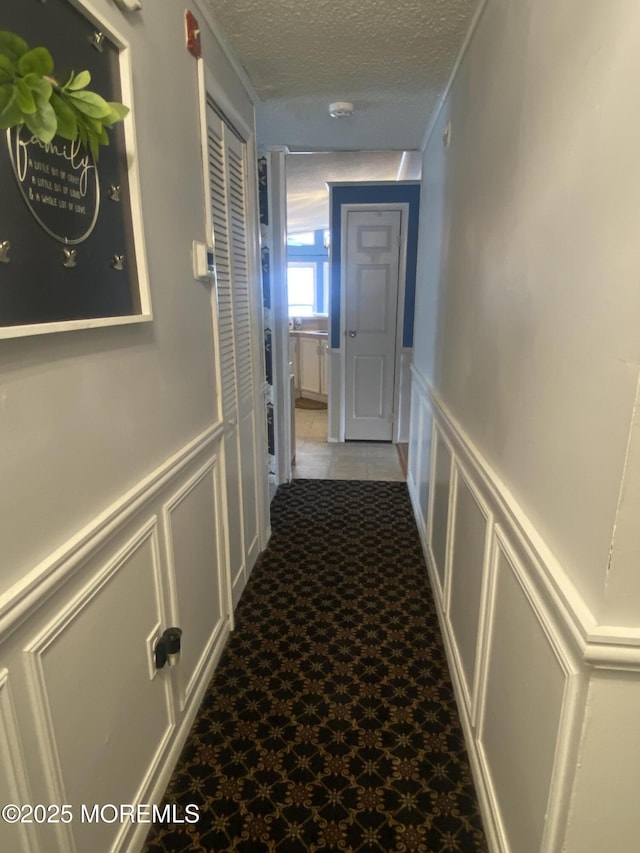 89 Seattle Slew Dr, Howell, NJ 07731 - hallway with a decorative wall, a textured ceiling, and a wainscoted wall