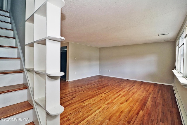 122 Oakwood Pl, Forked River, NJ 08731 - unfurnished room featuring stairs, a textured ceiling, light wood-style flooring, baseboards, and a baseboard heating unit