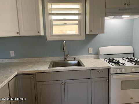128 Hamilton Ave, Seaside Heights, NJ 08751 - kitchen featuring white range with gas stovetop, under cabinet range hood, light countertops, and gray cabinets