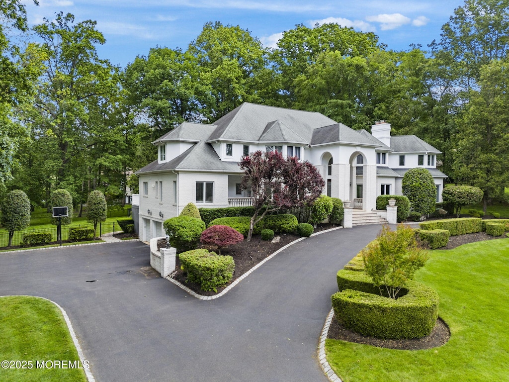 12 Round Hl, Holmdel, NJ 07733 - view of front of home featuring driveway, a garage, a chimney, a front yard, and view of wooded area