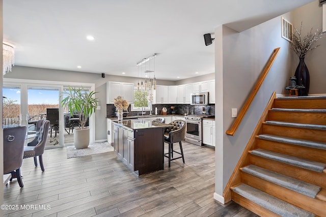 37 Florence Ave, Leonardo, NJ 07737 - kitchen featuring appliances with stainless steel finishes, backsplash, a kitchen bar, white cabinets, and a center island