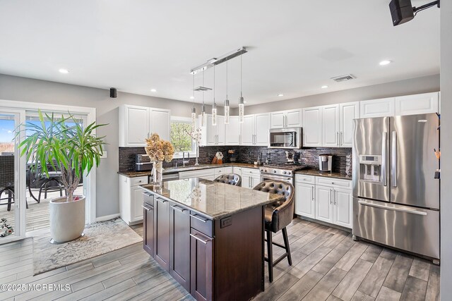 37 Florence Ave, Leonardo, NJ 07737 - kitchen with appliances with stainless steel finishes, light wood-style floors, dark stone countertops, backsplash, and white cabinets