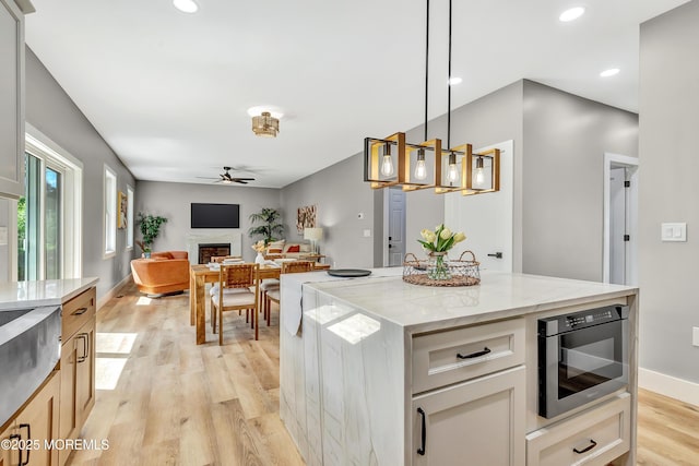 7 Cardinal Ave, Brick, NJ 08724 - kitchen featuring a ceiling fan, a fireplace, light wood finished floors, light stone counters, and hanging light fixtures