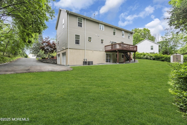16 W Ave, Gladstone, NJ 07934 - back of property featuring stairs, an attached garage, a deck, a storage shed, and a lawn