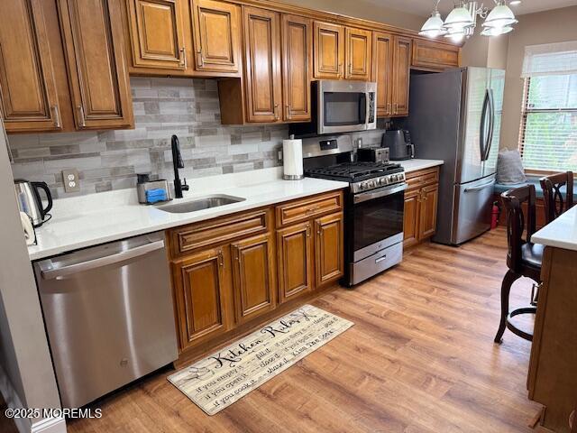 372 Oak Knoll Dr, Manalapan, NJ 07726 - kitchen featuring appliances with stainless steel finishes, a sink, brown cabinets, and light wood finished floors