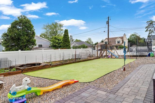 909 Amsterdam Ave, Toms River, NJ 08757 - fenced backyard with a trampoline, a playground, a garden, and a residential view