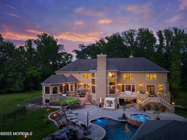 6 Bordens Brook Way, Holmdel, NJ 07733 - back of house at dusk featuring a wooden deck, an in-ground hot tub, stairway, stucco siding, and a chimney