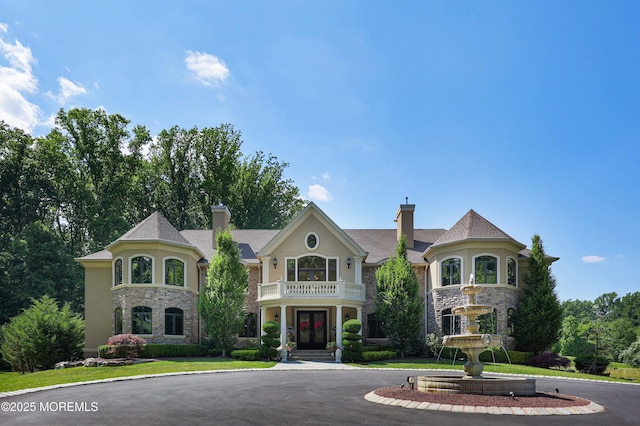 6 Bordens Brook Way, Holmdel, NJ 07733 - view of front of home with stone siding, french doors, a balcony, and a chimney