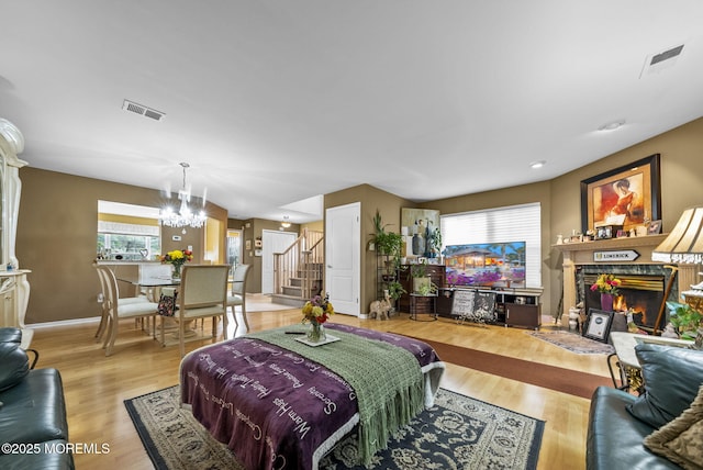 33 Oliver Ct Unit 1, Freehold, NJ 07728 - living room with a chandelier, a warm lit fireplace, stairway, and light wood-type flooring