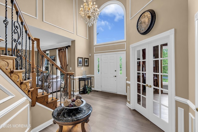 209 Shepard Way, Manalapan, NJ 07726 - entryway with french doors, a towering ceiling, a chandelier, wood finished floors, and stairway