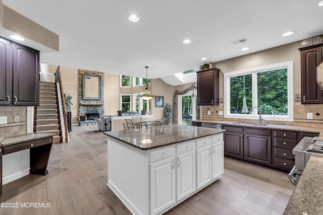 209 Shepard Way, Manalapan, NJ 07726 - kitchen with a sink, a kitchen island, backsplash, dark brown cabinetry, and light wood-style floors
