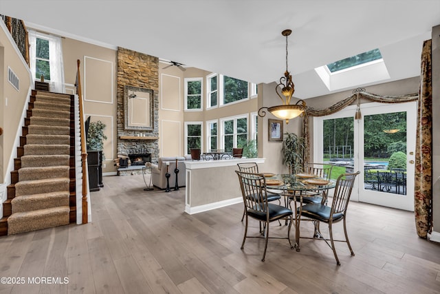 209 Shepard Way, Manalapan, NJ 07726 - dining area featuring a fireplace, a skylight, light wood-style flooring, stairway, and a towering ceiling