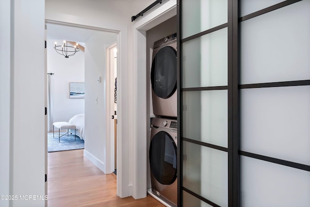 405 Ludlow Ave, Spring Lake, NJ 07762 - laundry area featuring stacked washer / drying machine, a chandelier, light wood-style floors, a barn door, and baseboards