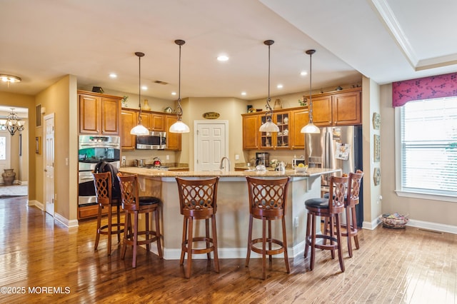 63 Wintergreen Dr, Manalapan, NJ 07726 - kitchen featuring stainless steel appliances, brown cabinetry, wood finished floors, glass insert cabinets, and pendant lighting