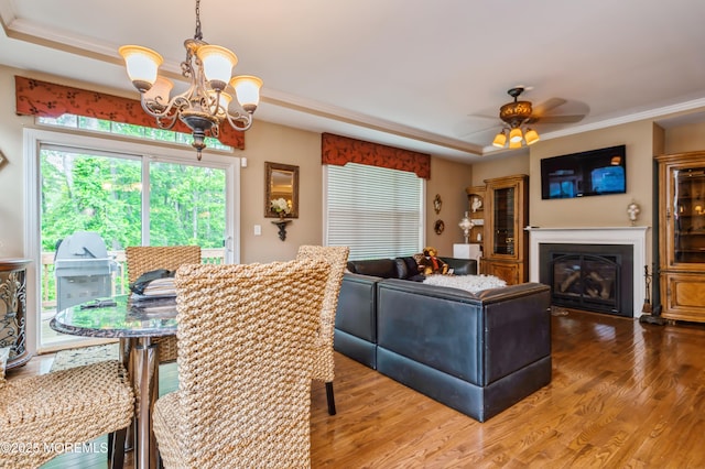 63 Wintergreen Dr, Manalapan, NJ 07726 - dining area featuring a chandelier, a raised ceiling, wood finished floors, crown molding, and a glass covered fireplace