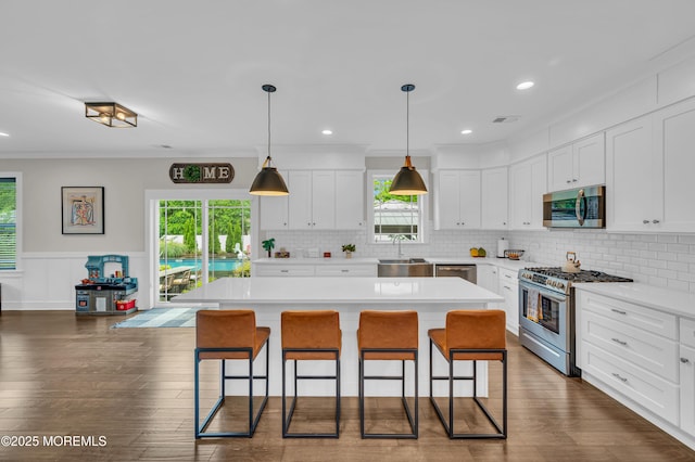 804 Linden Rd, Toms River, NJ 08753 - kitchen featuring appliances with stainless steel finishes, a breakfast bar area, light countertops, white cabinetry, and a wainscoted wall
