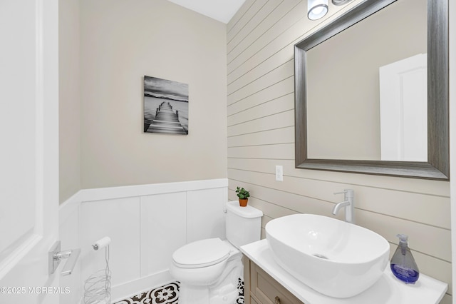 804 Linden Rd, Toms River, NJ 08753 - half bathroom featuring vanity, toilet, a decorative wall, wood walls, and a wainscoted wall