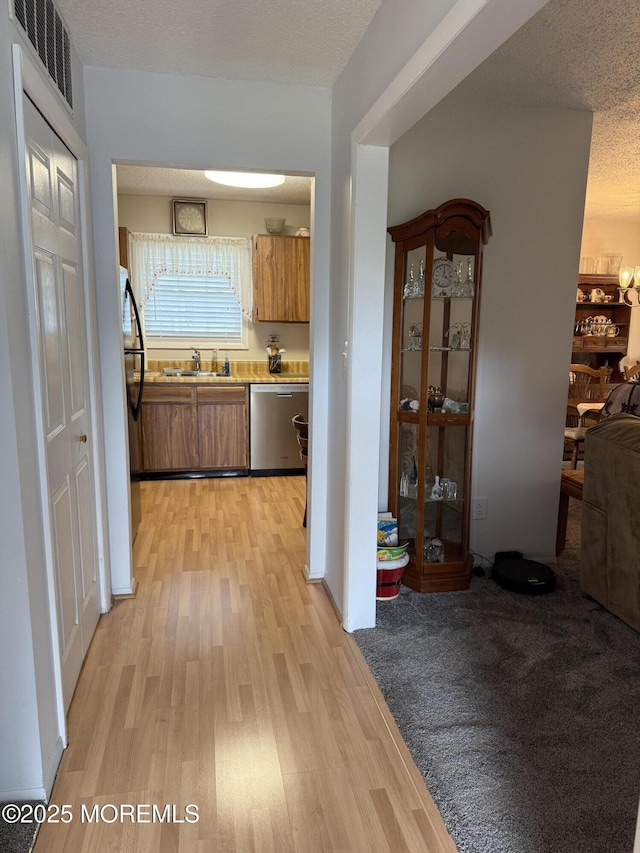132 Seaview Ave, Brick, NJ 08723 - kitchen with stainless steel dishwasher, freestanding refrigerator, a sink, light wood-style floors, and brown cabinetry