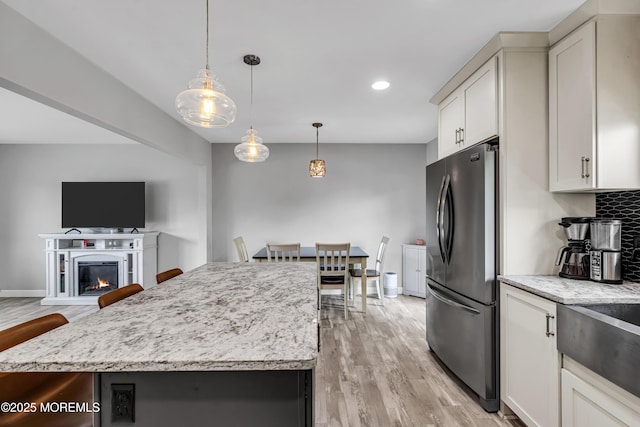 120 Lake Winnepesaukee Dr, Little Egg Harbor, NJ 08087 - kitchen featuring freestanding refrigerator, light wood-type flooring, a center island, light stone countertops, and decorative light fixtures