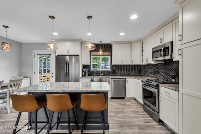 120 Lake Winnepesaukee Dr, Little Egg Harbor, NJ 08087 - kitchen with stainless steel appliances, a kitchen island, light wood-style floors, decorative backsplash, and a breakfast bar area