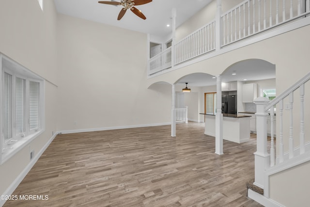 352 Leesville Rd, Jackson, NJ 08527 - unfurnished living room featuring arched walkways, decorative columns, ceiling fan, a high ceiling, and light wood-style floors