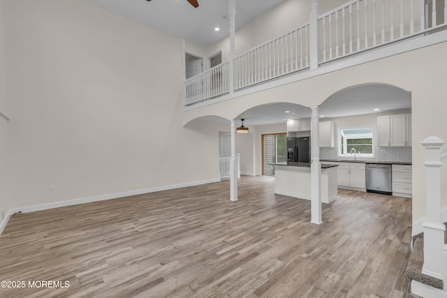 352 Leesville Rd, Jackson, NJ 08527 - unfurnished living room with ceiling fan, light wood-style floors, arched walkways, ornate columns, and a towering ceiling