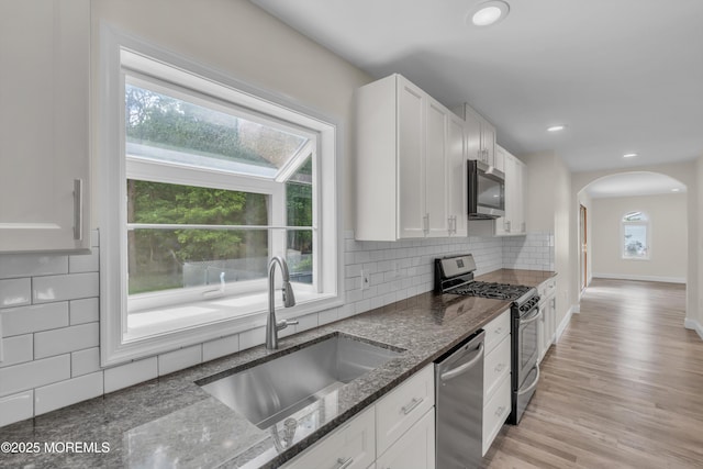 352 Leesville Rd, Jackson, NJ 08527 - kitchen with stainless steel appliances, a sink, arched walkways, dark stone counters, and white cabinets
