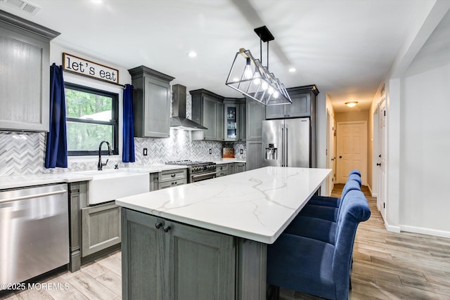 25 Merritt Ter, Matawan, NJ 07747 - kitchen featuring appliances with stainless steel finishes, wall chimney exhaust hood, a sink, a center island, and gray cabinetry