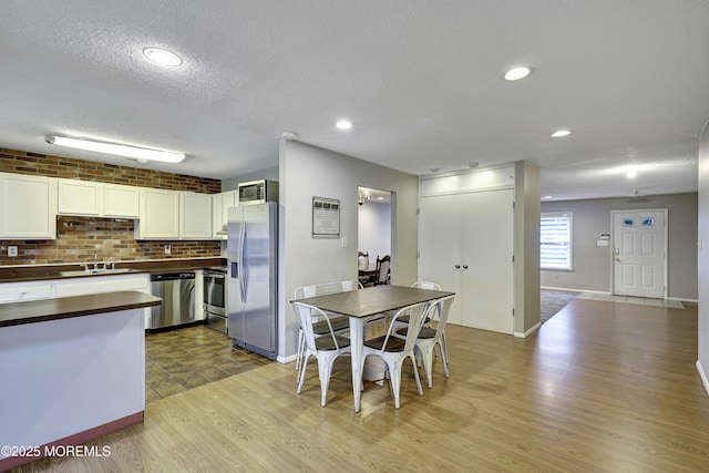 1299 E County Line Rd, Lakewood, NJ 08701 - kitchen with stainless steel appliances, a sink, light wood-style flooring, white cabinets, and a textured ceiling