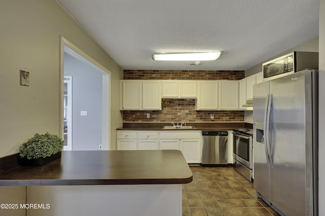 1299 E County Line Rd, Lakewood, NJ 08701 - kitchen with stainless steel appliances, white cabinetry, a sink, a peninsula, and tasteful backsplash
