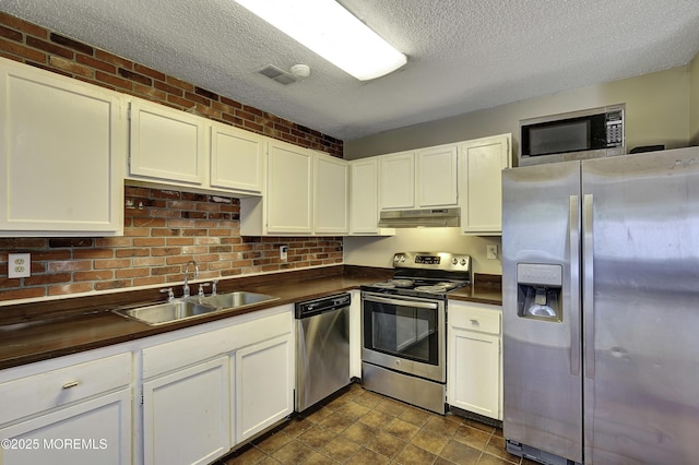 1299 E County Line Rd, Lakewood, NJ 08701 - kitchen with appliances with stainless steel finishes, under cabinet range hood, a sink, a textured ceiling, and white cabinets