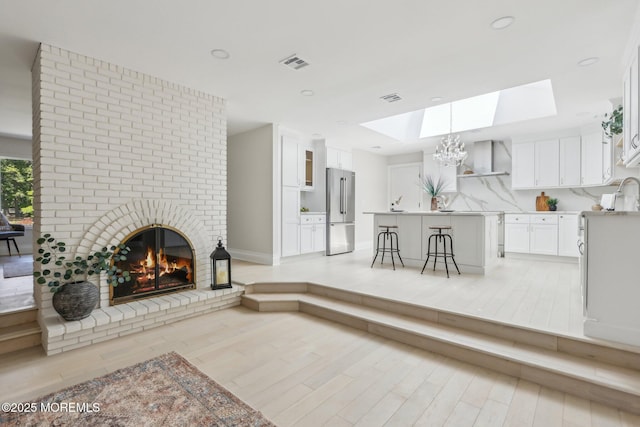8 Olden Ct, Colts Neck, NJ 07722 - living room with a skylight, a fireplace, light wood-type flooring, and a chandelier