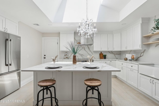 8 Olden Ct, Colts Neck, NJ 07722 - kitchen with high end fridge, open shelves, light wood-type flooring, and a breakfast bar