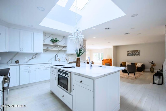 8 Olden Ct, Colts Neck, NJ 07722 - kitchen with a skylight, a kitchen island, open shelves, a chandelier, and light stone counters