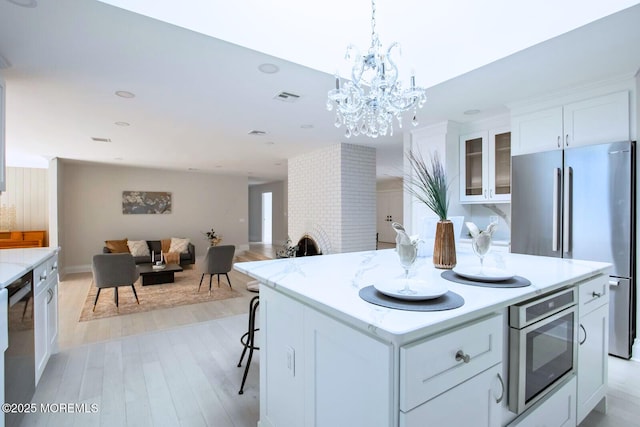 8 Olden Ct, Colts Neck, NJ 07722 - kitchen with stainless steel appliances, white cabinetry, light wood-type flooring, a kitchen island, and glass insert cabinets