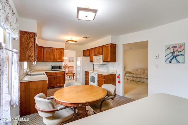 2 Thames Pl, Brick, NJ 08723 - kitchen with white appliances, light countertops, carpet floors, brown cabinets, and a sink
