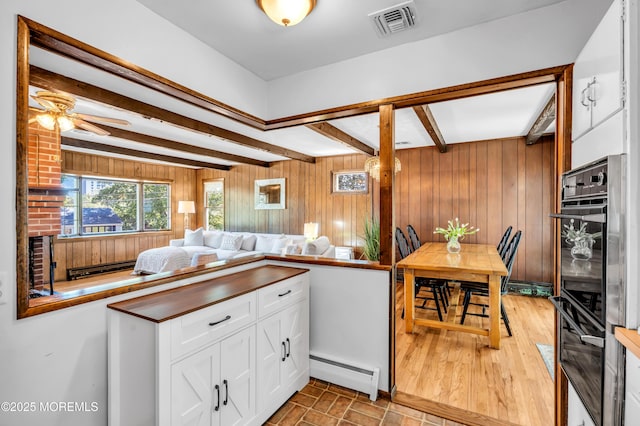 162 Delaware Ave, Atlantic Highlands, NJ 07716 - kitchen with a baseboard radiator, beamed ceiling, wooden walls, white cabinetry, and ceiling fan