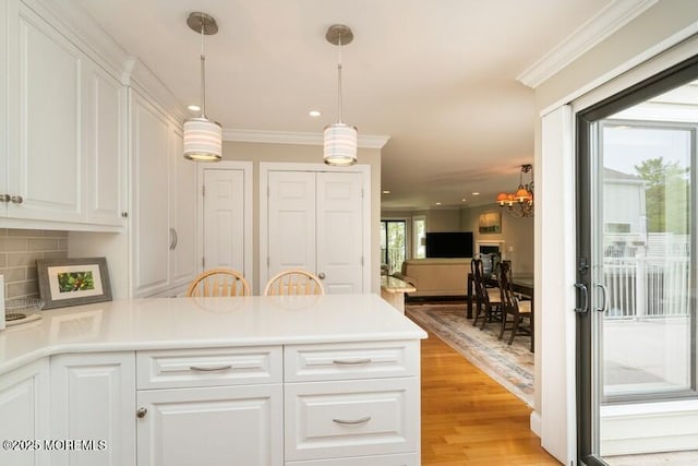 580 Patten Ave # 53, Long Branch, NJ 07740 - kitchen with white cabinets, backsplash, a peninsula, light wood-type flooring, and ornamental molding